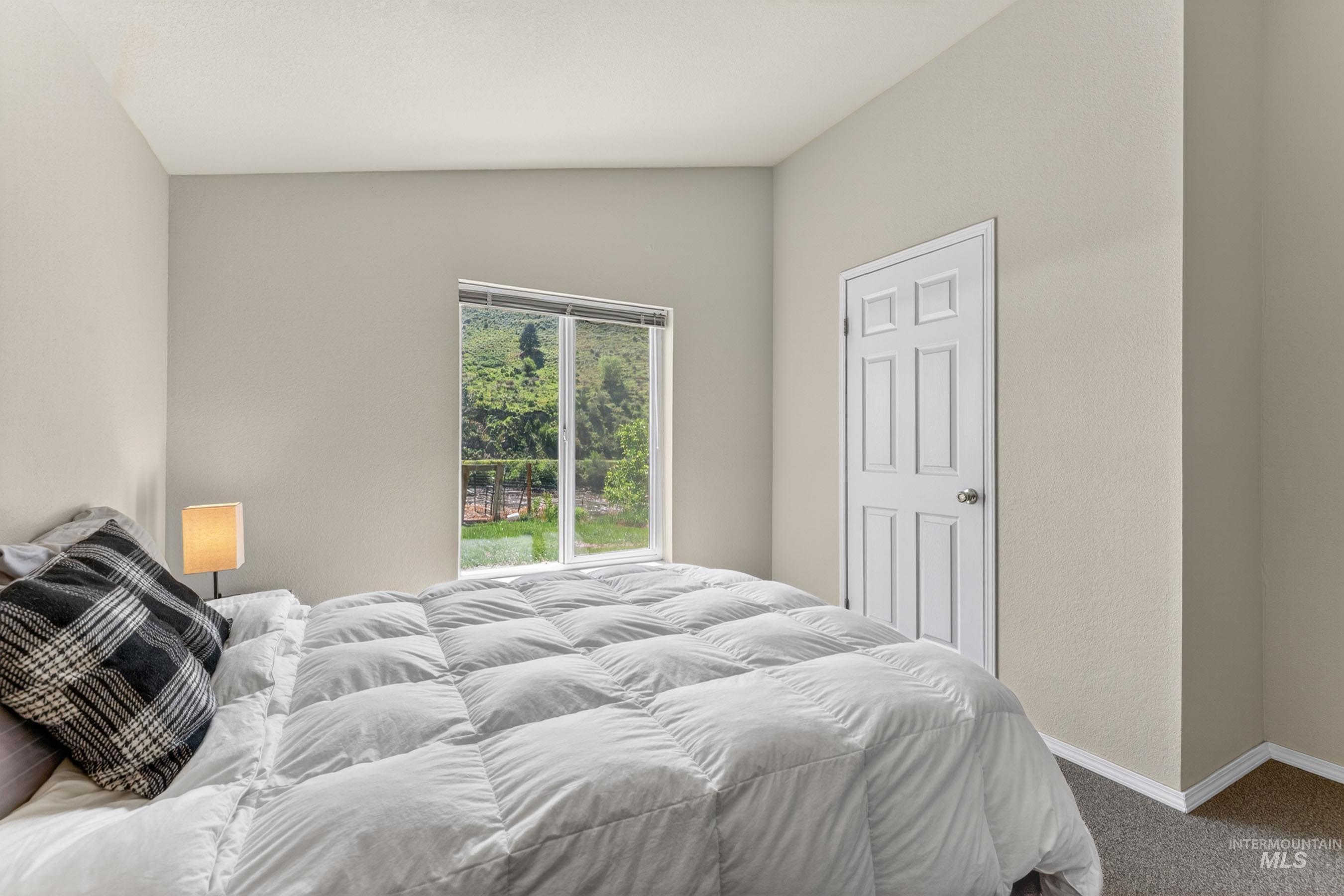 151 Cow Creek Road Lucile, ID 83542 - Photo 29 of 50 Bright room featuring a window with green outdoor scenery, light neutral wall paint, white trim, and gray carpet flooring