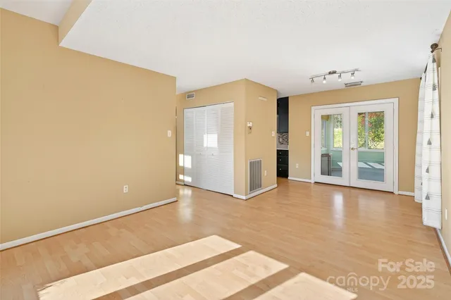 a view of an empty room with wooden floor and a window