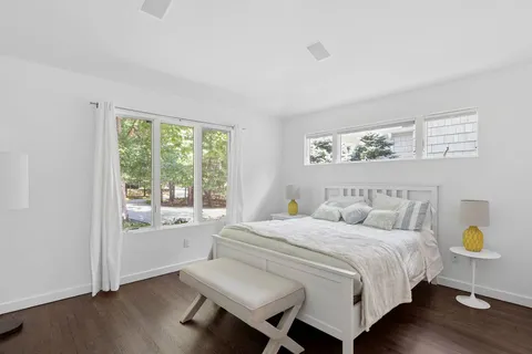 a bedroom with a bed a window and painting on the wall