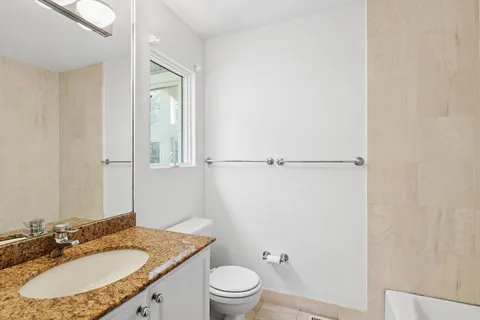 a bathroom with a granite countertop sink toilet a mirror and vanity