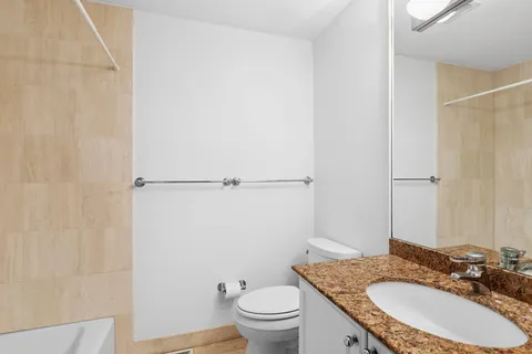 a bathroom with a granite countertop sink toilet and a mirror