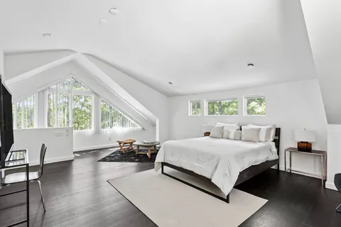 a bedroom with a large bed and large windows