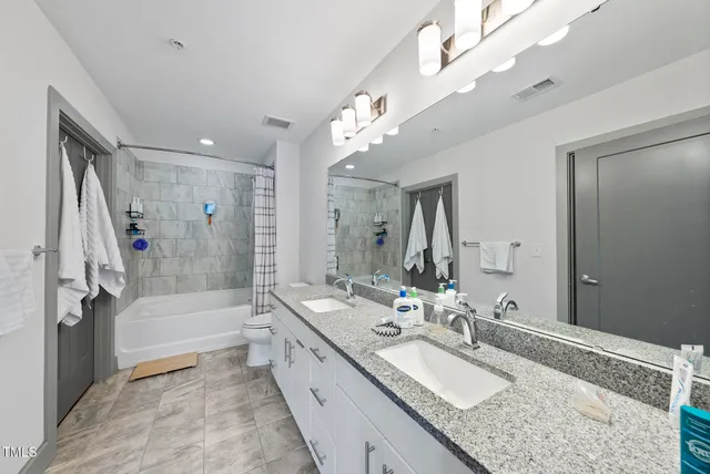 a bathroom with a granite countertop double vanity sink a mirror and a bathtub