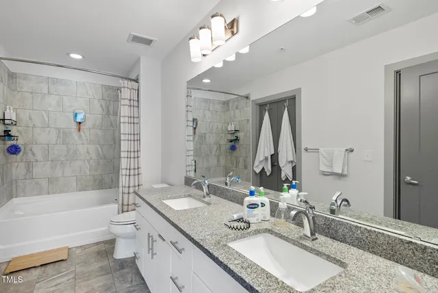 a bathroom with a granite countertop double vanity sink mirror double and bathtub