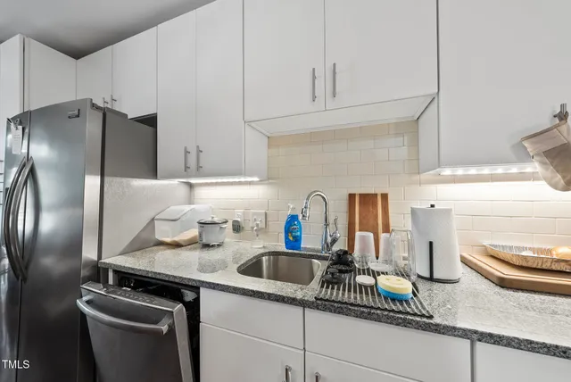 a kitchen with stainless steel appliances a sink a refrigerator and cabinets