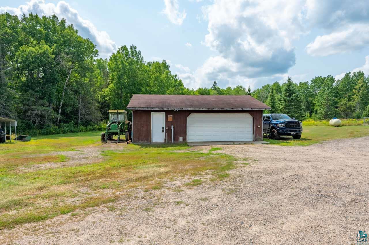 3201 Wilderness Road Makinen, MN 55763 - Photo 2 of 52 Detached outbuilding with a single garage door and separate entry door, featuring a gravel driveway and surrounding green landscape