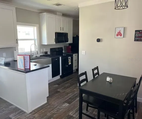 a kitchen with stainless steel appliances a dining table chairs microwave and sink