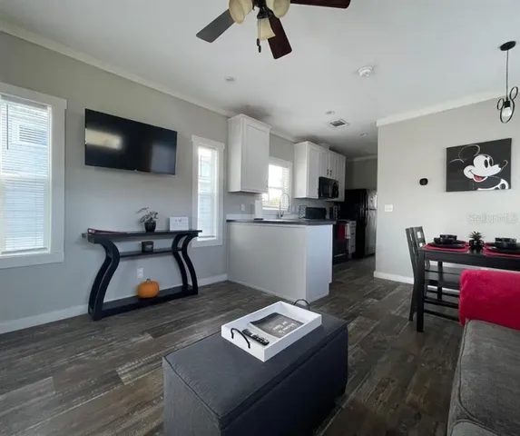 a living room with furniture and a flat screen tv with kitchen view