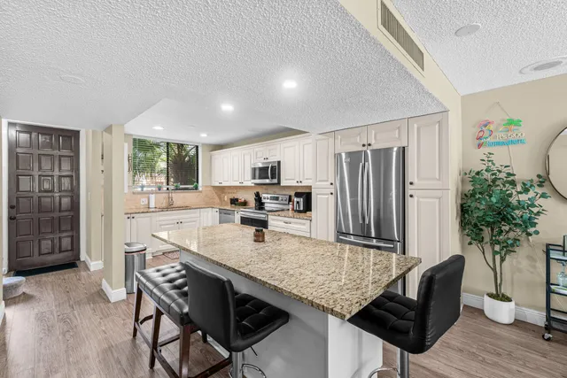 a kitchen with granite countertop white cabinets and stainless steel appliances