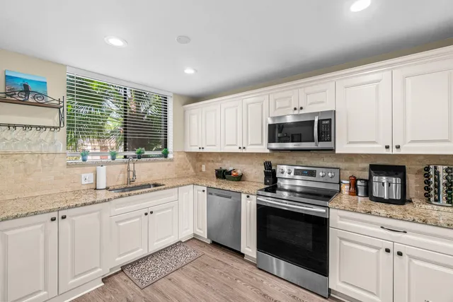 a kitchen with granite countertop white cabinets and stainless steel appliances