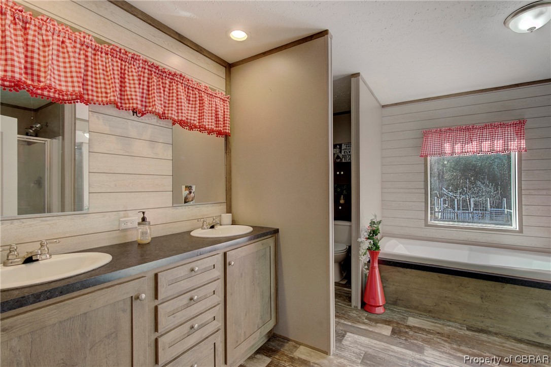 3029 Carsley Road Dendron, VA 23839 - Photo 5 of 26 Full bathroom with toilet, wood walls, wood-type flooring, dual vanity, and ornamental molding