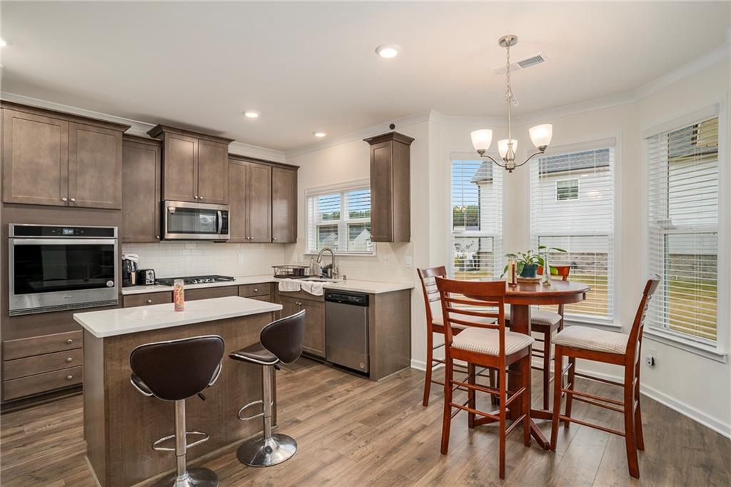 13709 Whitman Lane Covington, GA 30014 - Photo 11 of 36 a kitchen with stainless steel appliances granite countertop a stove top oven a sink dishwasher a dining table and chairs with wooden floor