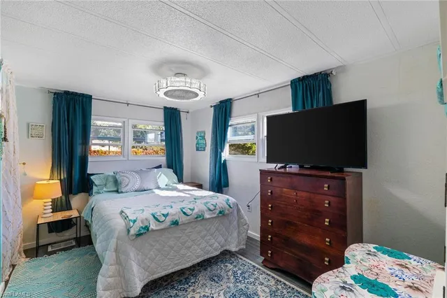 a bedroom with a bed and flat tv screen on dresser