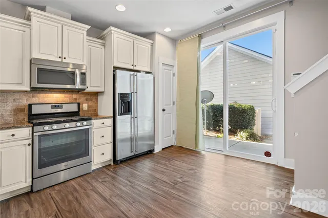 a kitchen with stainless steel appliances granite countertop a refrigerator and a stove top oven