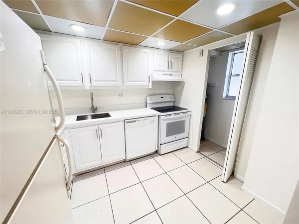 a kitchen with a sink a refrigerator and cabinets