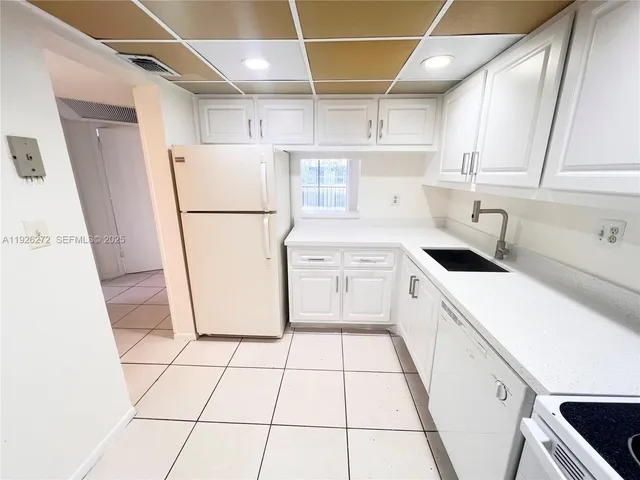 a kitchen with a sink a refrigerator and cabinets