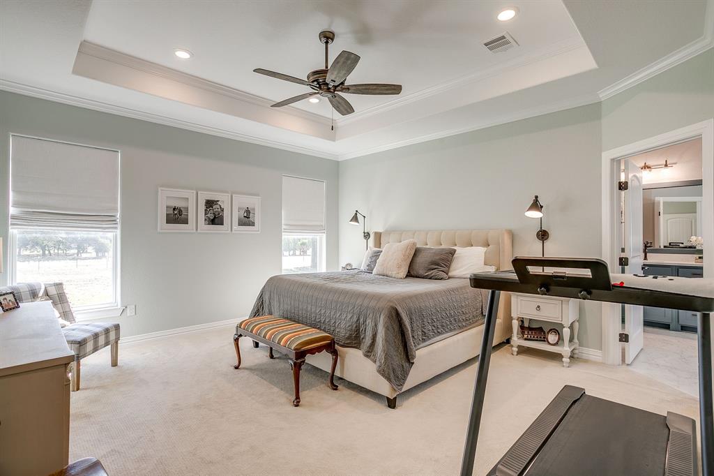 229 Oak Tree Drive Poolville, TX 76487 - Photo 18 of 40 a spacious bedroom with a bed a chandelier and window