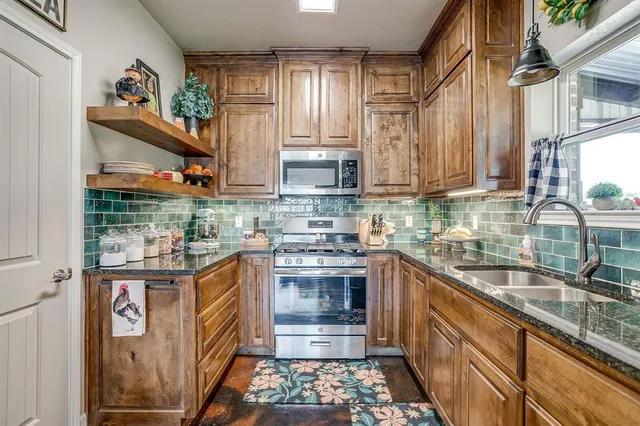 a kitchen with stainless steel appliances granite countertop a sink stove and cabinets