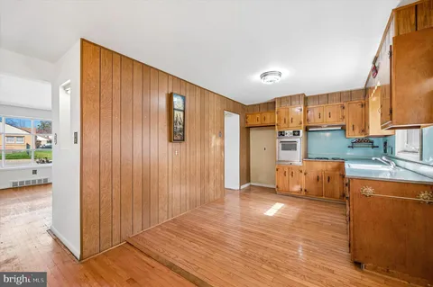 a view of kitchen with stainless steel appliances wooden floor and chair