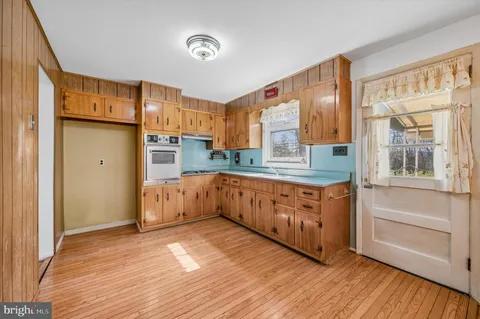 a kitchen with stainless steel appliances granite countertop a refrigerator a sink dishwasher a stove and white countertops with wooden floor