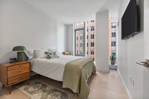 a bedroom with a bed a flat screen tv and dresser