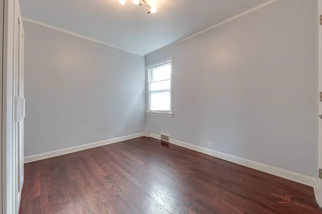 an empty room with wooden floor and window