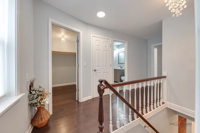 a view of a hallway to a room with wooden floor and staircase