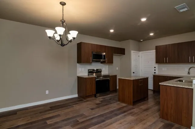 a large kitchen with stainless steel appliances granite countertop a sink dishwasher a stove and a microwave oven on granite countertops