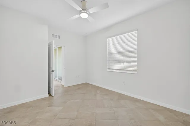 an empty room with a ceiling fan and a window