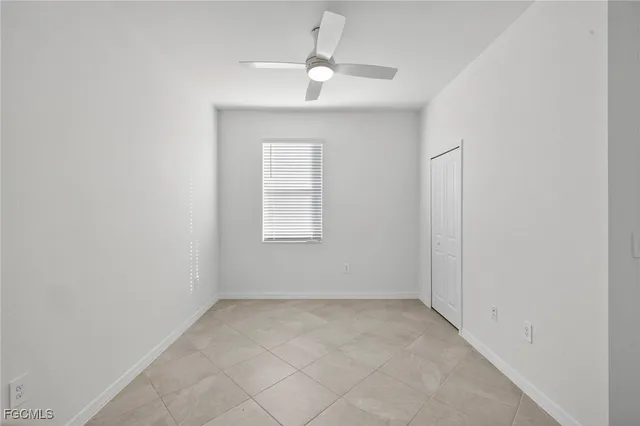 an empty room with a window and a fan