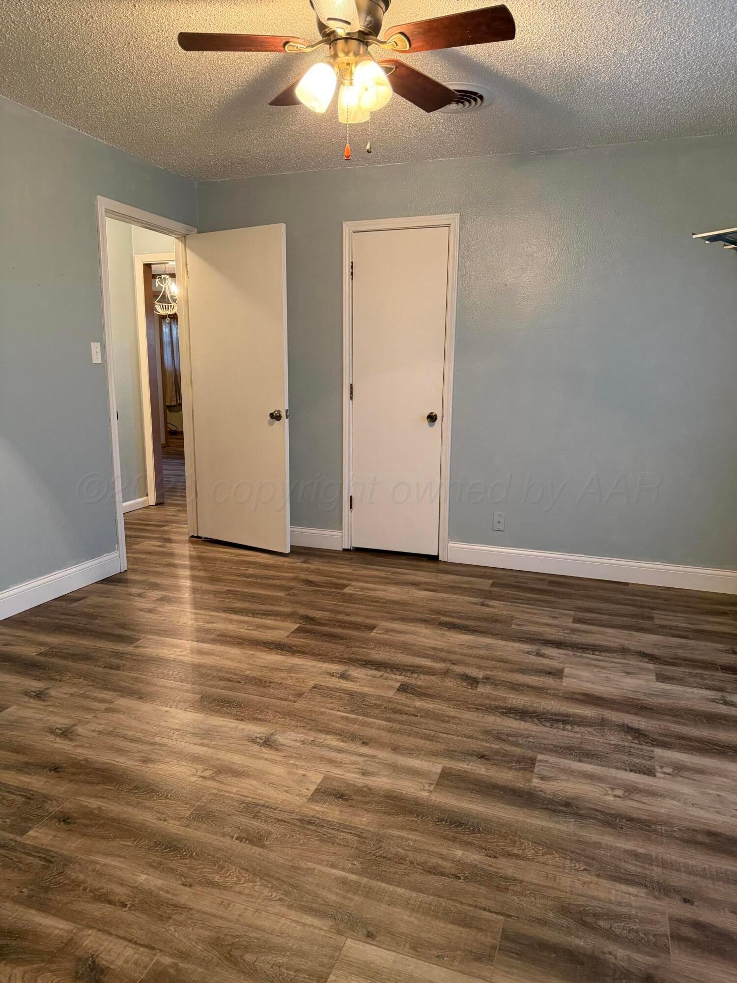 1313 Davis Street Borger, TX 79007 - Photo 11 of 15 an empty room with wooden floor fan and window