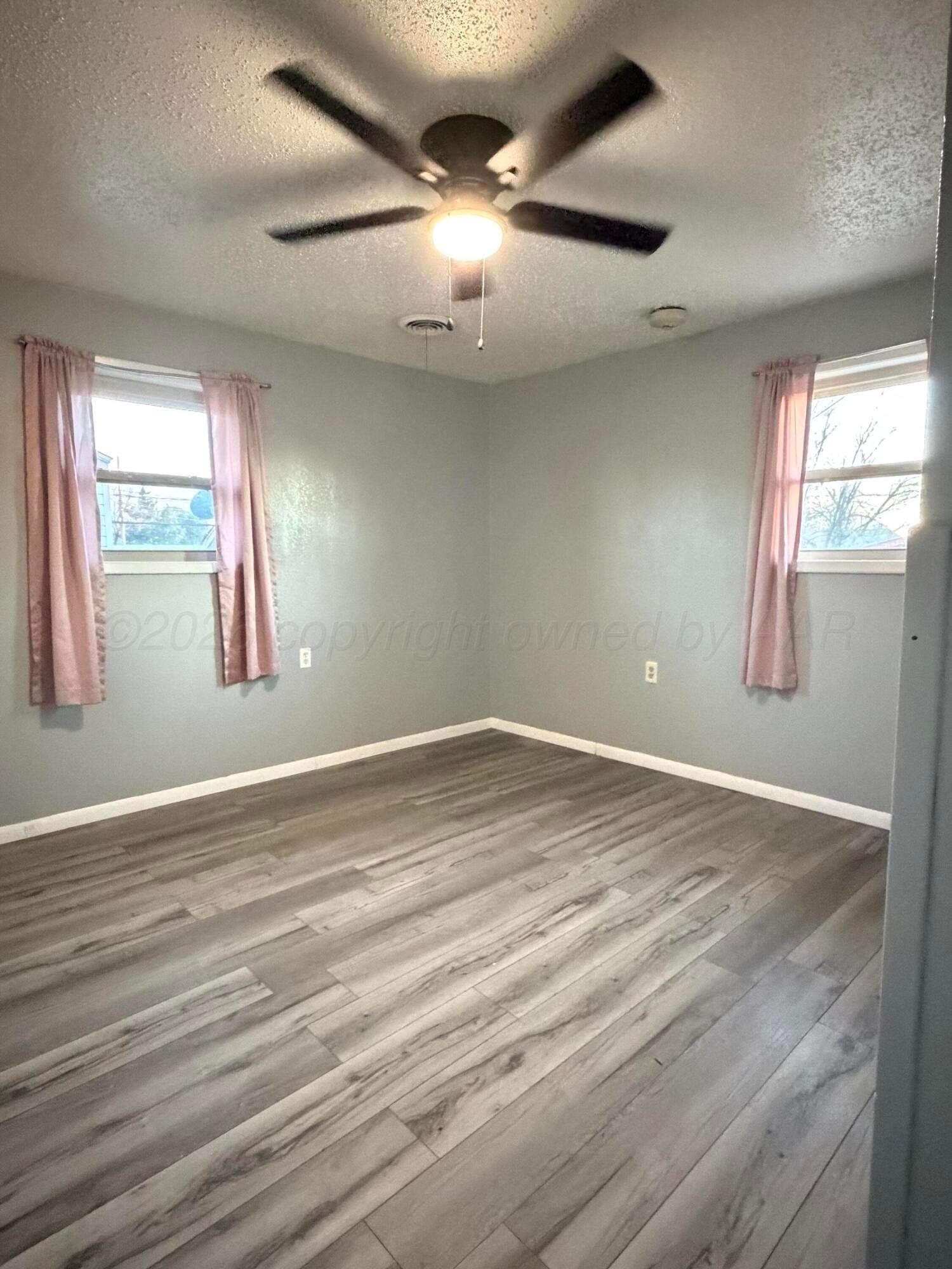 1313 Davis Street Borger, TX 79007 - Photo 15 of 15 an empty room with wooden floor and windows