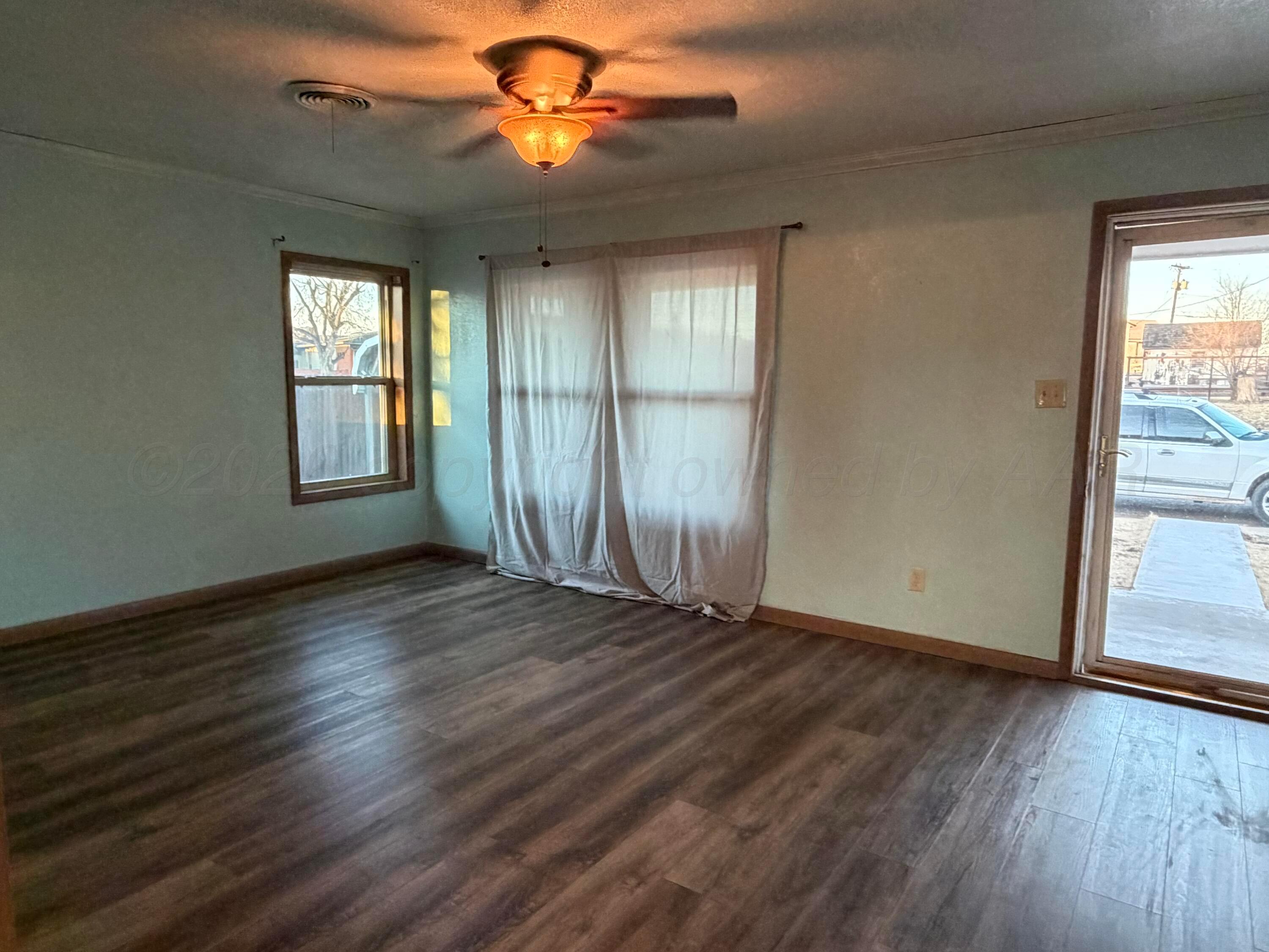 1313 Davis Street Borger, TX 79007 - Photo 4 of 15 a view of an empty room with a window and wooden floor