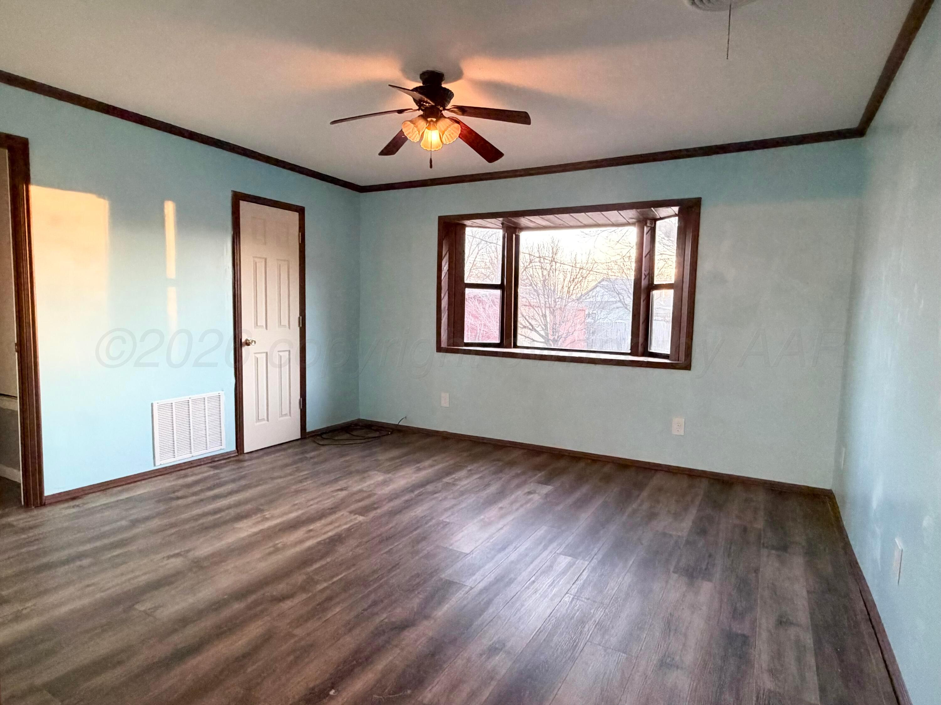 1313 Davis Street Borger, TX 79007 - Photo 9 of 15 an empty room with wooden floor chandelier fan and windows