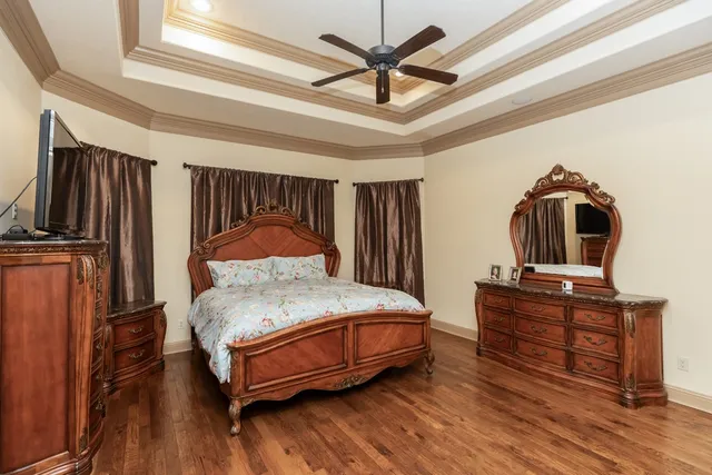 a bedroom with a bed a dresser and wooden floor