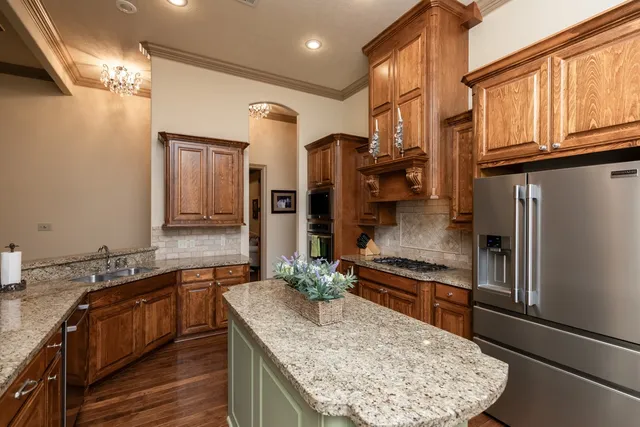 a kitchen with stainless steel appliances granite countertop a sink a stove and a refrigerator