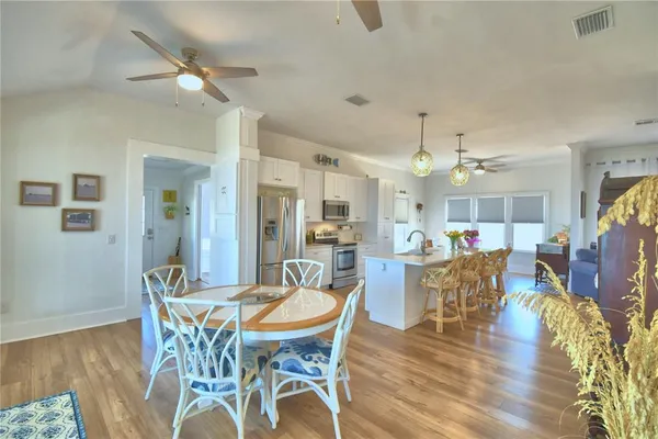a large white kitchen with a large island oven a stove white cabinetry and chairs