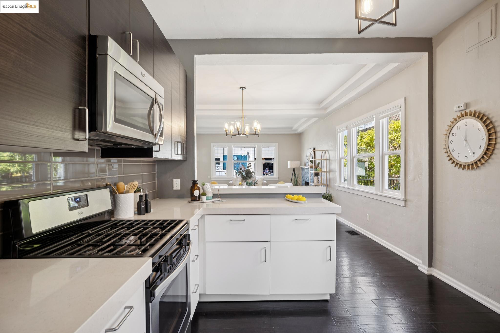 1092 Dwight Way Berkeley, CA 94710 - Photo 16 of 36 Kitchen featuring stainless steel appliances, a peninsula, backsplash, dark wood-type flooring, and a chandelier