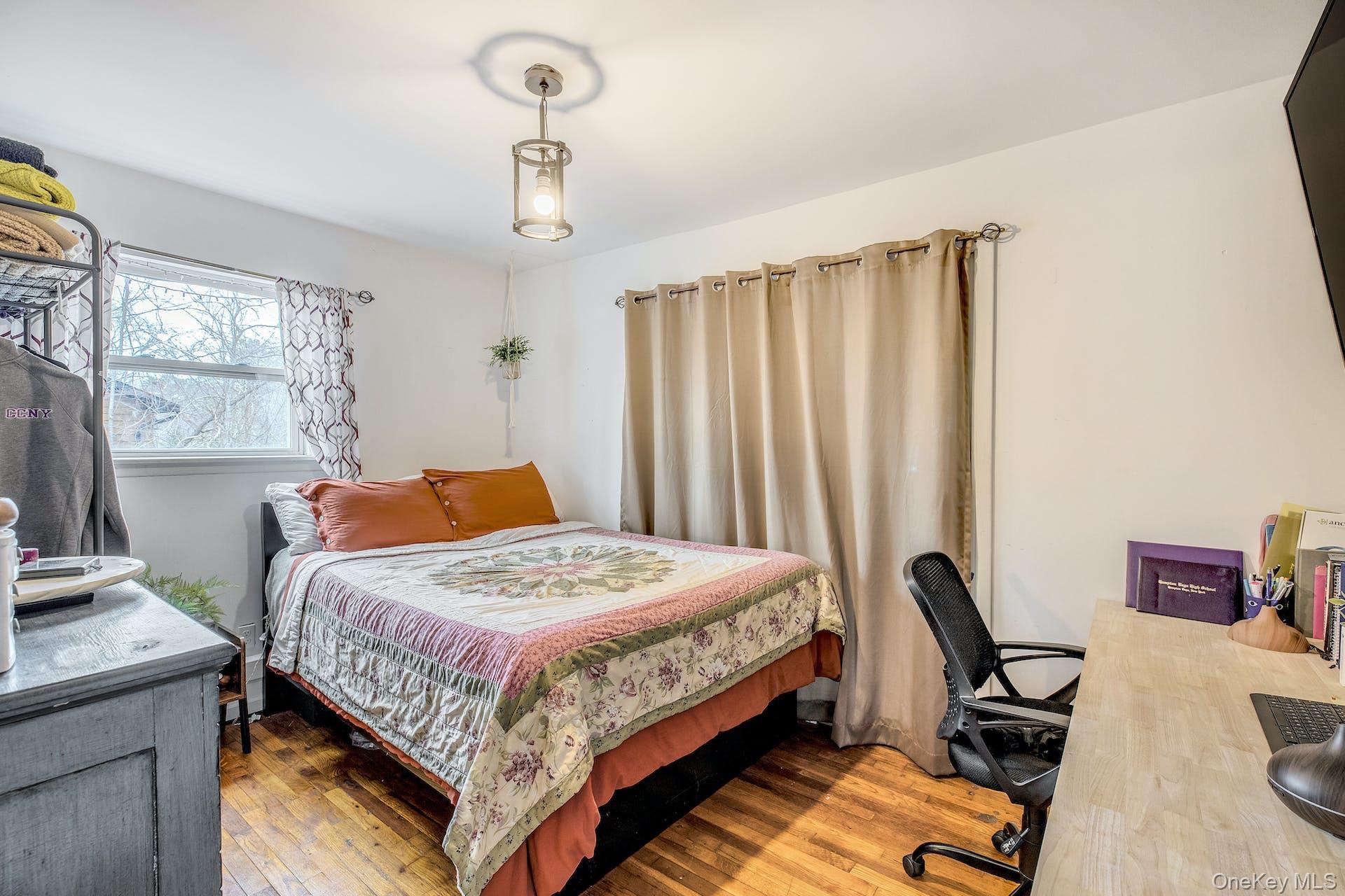 7 George Street Hampton Bays, NY 11946 - Photo 9 of 11 Bedroom featuring wood-finish flooring, a window with patterned drapes, a ceiling-mounted light fixture, and light-toned walls