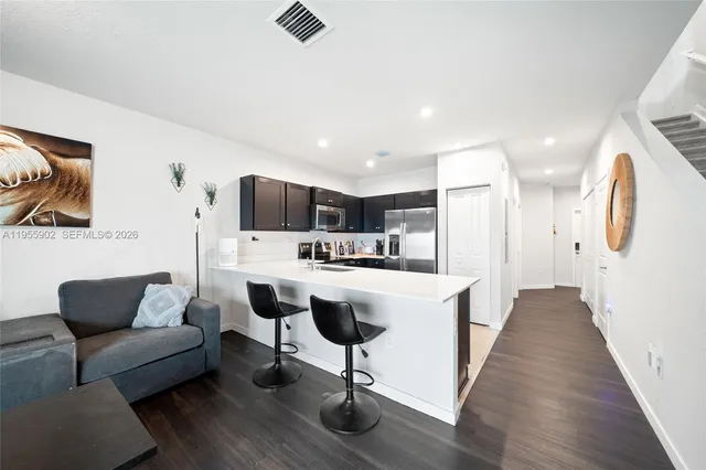 a living room with stainless steel appliances furniture and a kitchen view