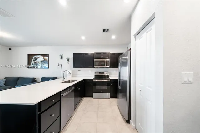 a kitchen with a sink a stove top oven and stainless steel appliances