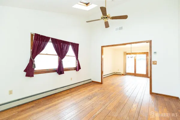a view of an empty room with wooden floor and a window