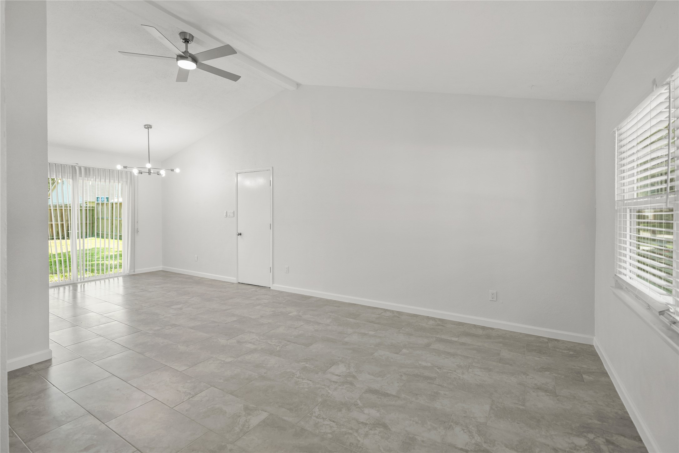 6610 Blue Ridge Drive Richmond, TX 77469 - Photo 3 of 24 This spacious, open-concept living area features a high ceiling with a modern ceiling fan, large windows for natural light, and a sliding glass door leading to the backyard. The neutral tile flooring and light walls create a bright, airy atmosphere.