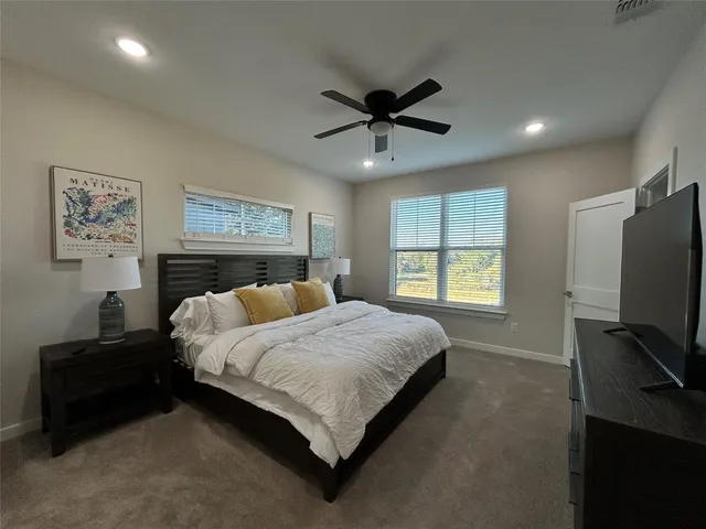 a bedroom with a bed a couch and a flat screen tv