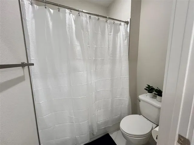 a white toilet sitting next to a shower curtain