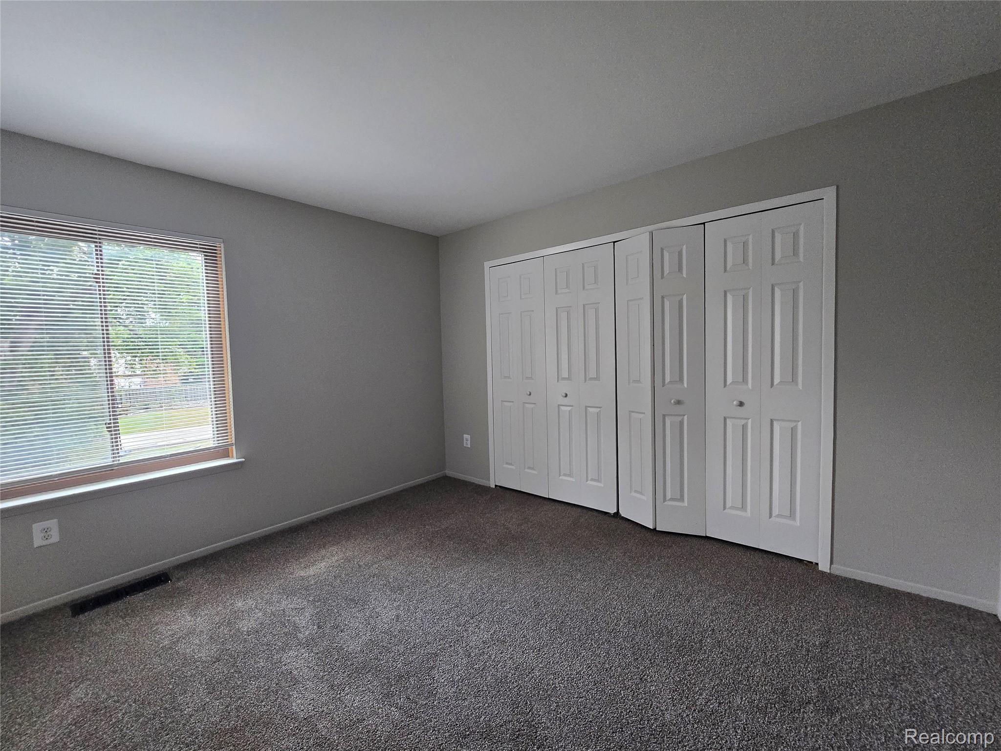 23568 Lahser Road Southfield, MI 48033 - Photo 9 of 18 Neutral wall paint, carpet flooring, two bi-fold door closets, and a large window