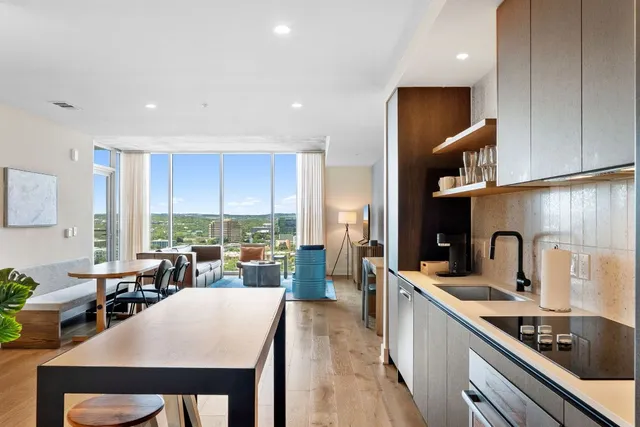 a kitchen with stainless steel appliances a refrigerator a sink a stove a dining table and chairs