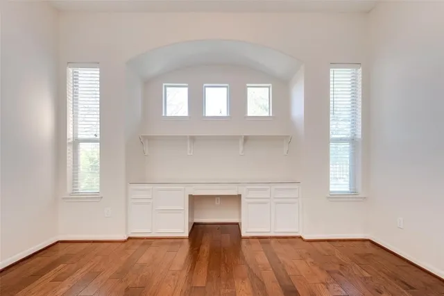 an empty room with wooden floor and windows