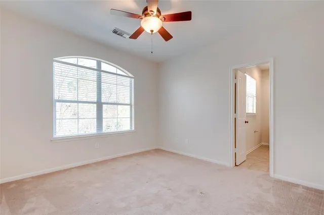 an empty room with windows and chandelier fan