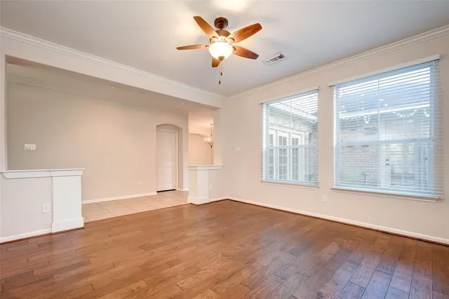 a view of an empty room with a window and wooden floor